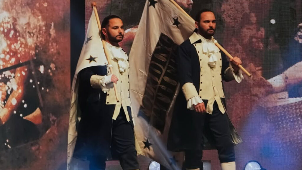 Nick and Matt Jackson (the Young Bucks) walk to the ring in 1700s clothes carrying flags at AEW Double or Nothing 2025.